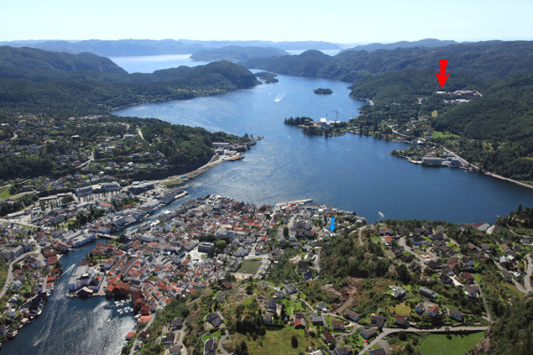 Oversiktsbilde over Flekkefjord med vår fabrikk markert (rød pil) og hvor vi holdt til før 1975 (blå pil)